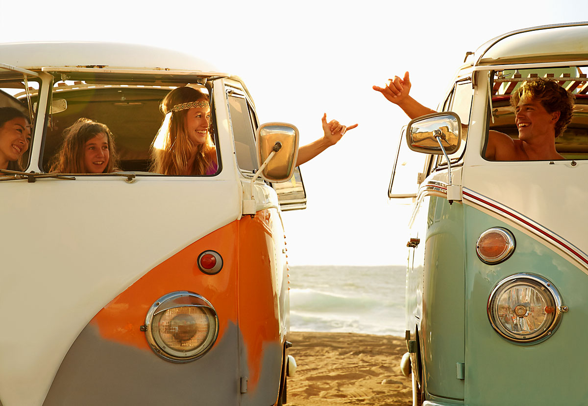 People making hand gestures in vans on beach